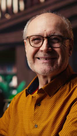 vertical video senior man at university wearing glasses reading documents with focus