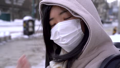 pretty happy young girl smiling and waving into camera while wearing facemask