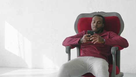 man using mobile phone in a red chair