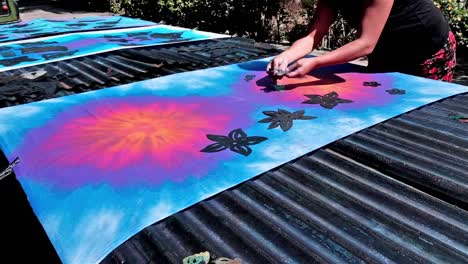 using stencils onto a tie dye fabric to bleach patterns into the colour