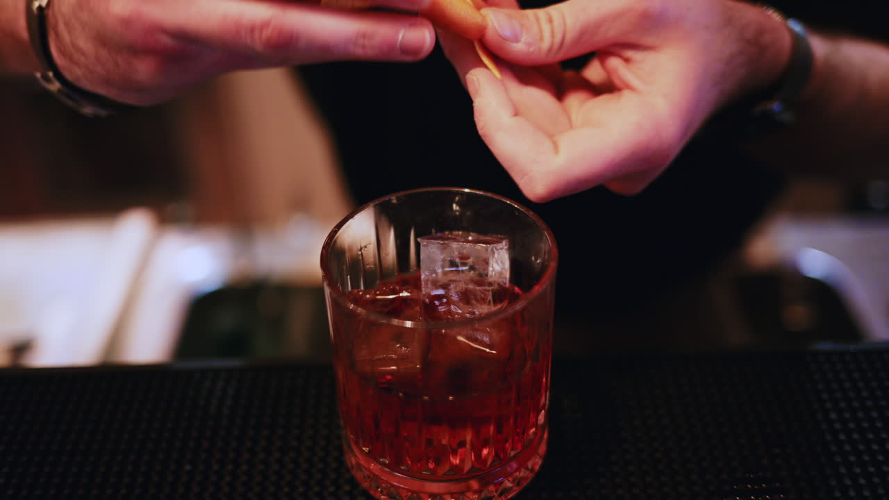 Un barista aggiunge una scorza d'arancia a un cocktail appena preparato