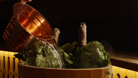 pouring water on oak leaves in a sauna