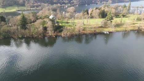 rising revealing drone view of green island in dark lake with sailboats moored