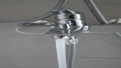 closeup of a chrome faucet with water running in a modern bathroom