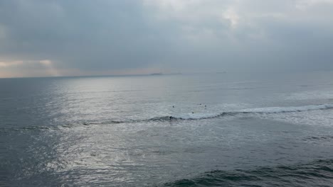 Surfers-Riding-Ocean-Waves:-A-Spectacular-Scene-with-Cloudy-Sky-Adding-Drama-to-the-Surfing-Adventure