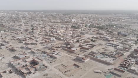 Aerial drone footage capturing a Tunisian town in a semi-arid desert region, showcasing residential neighborhoods and scattered greenery