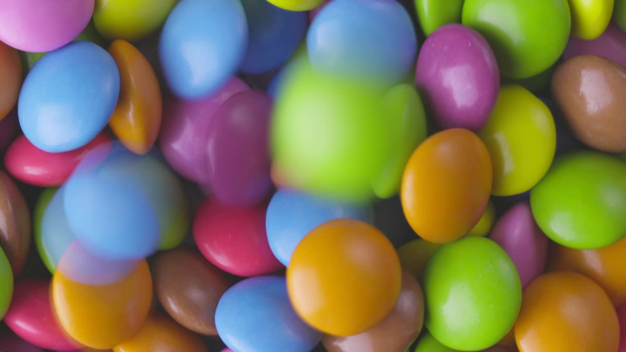 movimiento lento de primer plano de caramelos de chocolate redondos de colores, dragee. rotación y caída de caramellos de chocolate multicolores