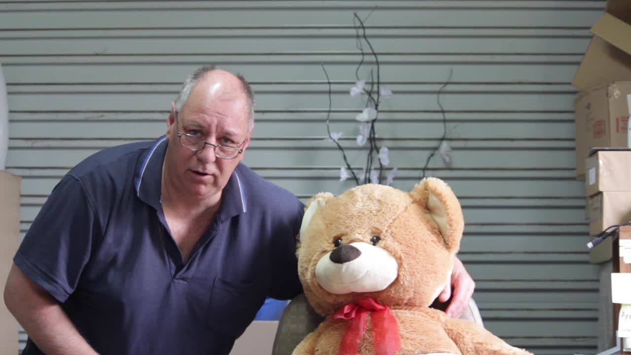 Male middle aged man having a photo with a toy teddy bear.