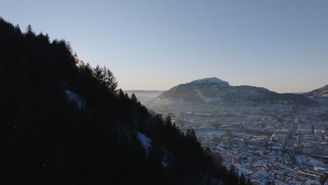 aerial shot along a snowy hillside in bergen on a beautiful winter day