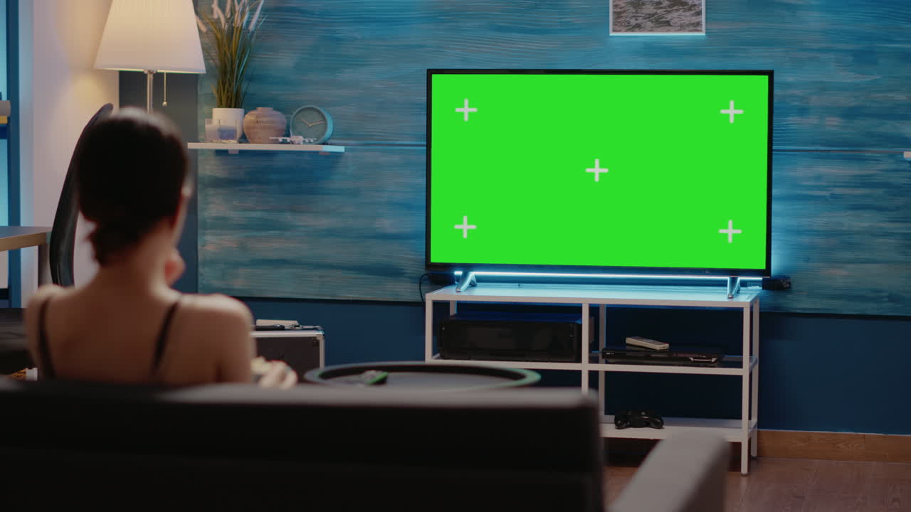 Young adult watching green screen display on television