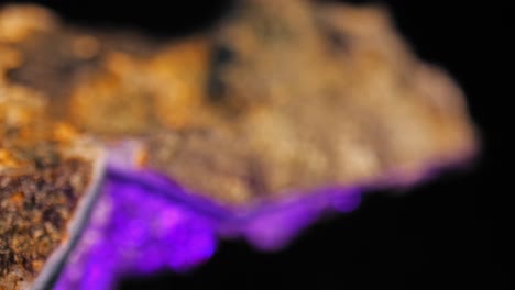 panorámica cinematográfica suave de la capa superficial detallada de un cristal de amatista púrpura iluminado sobre un fondo negro