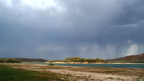 captivating time-lapse: summer rainstorm over the fast-flowing river with majestic mountains, creating a dusty and arid atmosphere. moody sky, rain clouds.