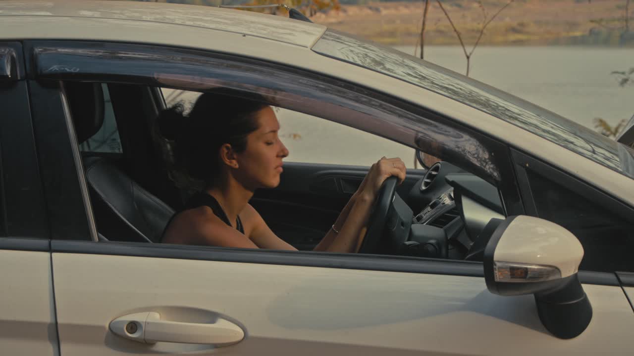 Woman Driving a Car Near a Lake