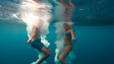 young couple diving and splashing underwater