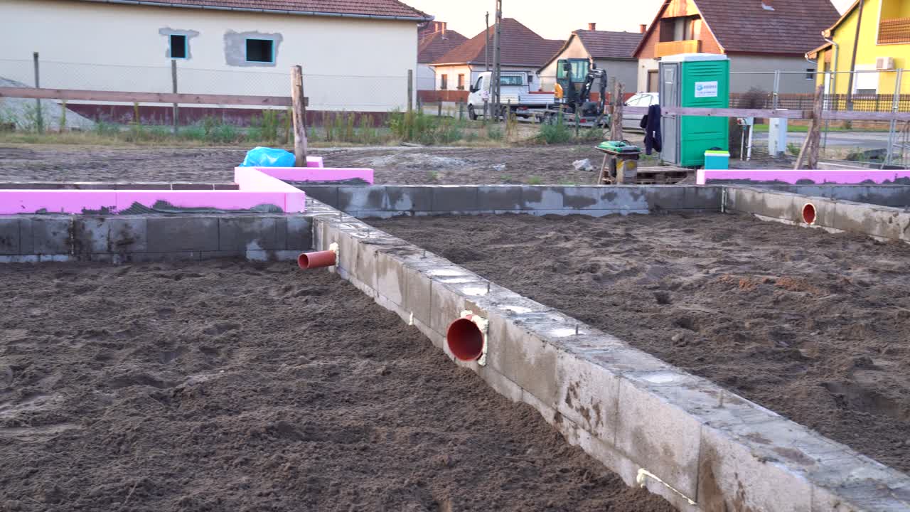 House foundation with visible plumbing and insulation during early construction phase