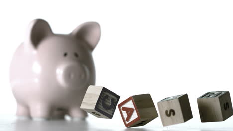 bloques de alfabeto deletreando dinero cayendo delante de una alcancía