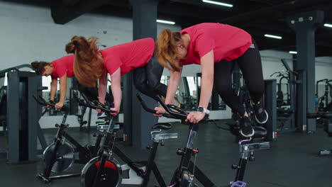 Grupo-De-Mujeres-Atléticas-Montando-En-Rutina-De-Entrenamiento-De-Bicicleta-Estacionaria-Giratoria-En-El-Gimnasio,-Pérdida-De-Peso-En-Interiores