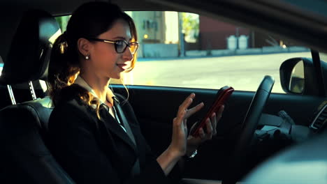 attractive caucasian business woman in a parked car, dials her phone and has a happy phone call