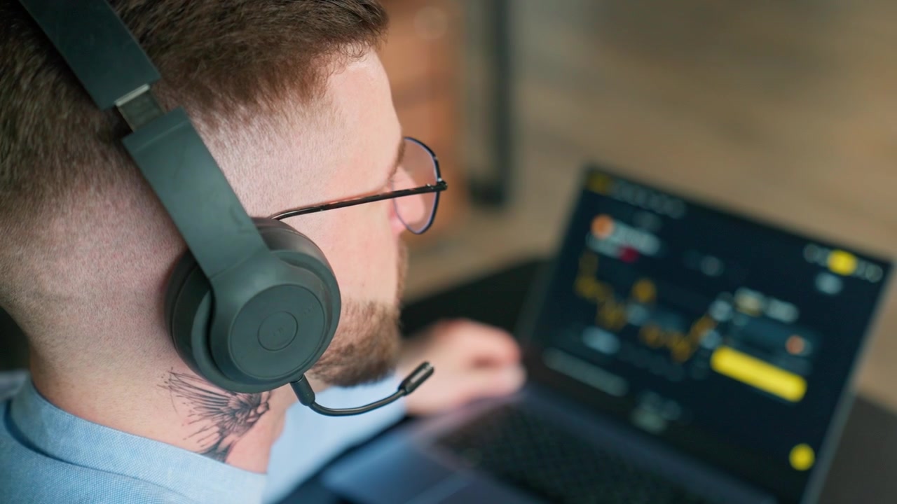 Man in Headphones Analyzing Financial Data on Laptop