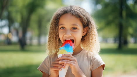 young girl enjoying a colorful snow cone outdoors