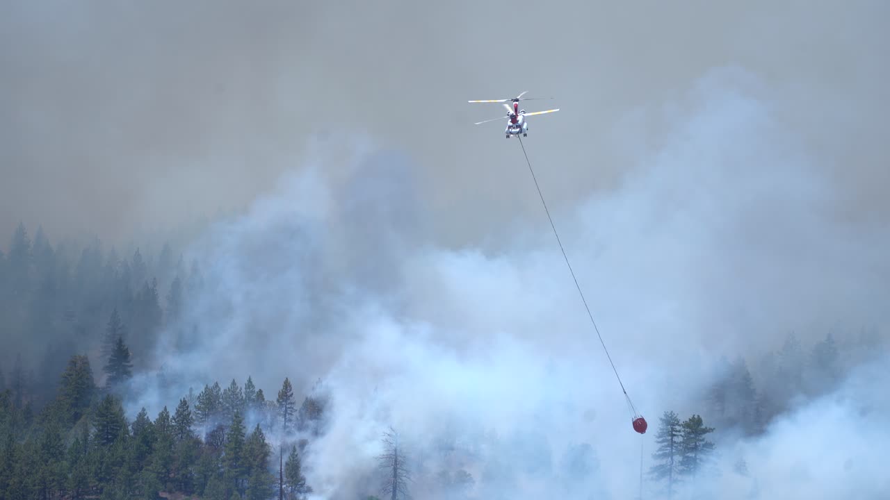 Helicóptero lanza agua sobre un incendio forestal
