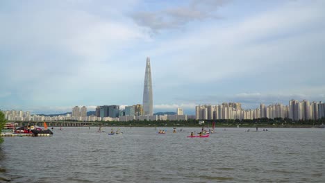 Actividad-De-Deportes-Acuáticos-En-El-Río-Han-Con-El-Rascacielos-Lotte-World-Tower-En-Segundo-Plano-En-Seúl,-Corea-Del-Sur