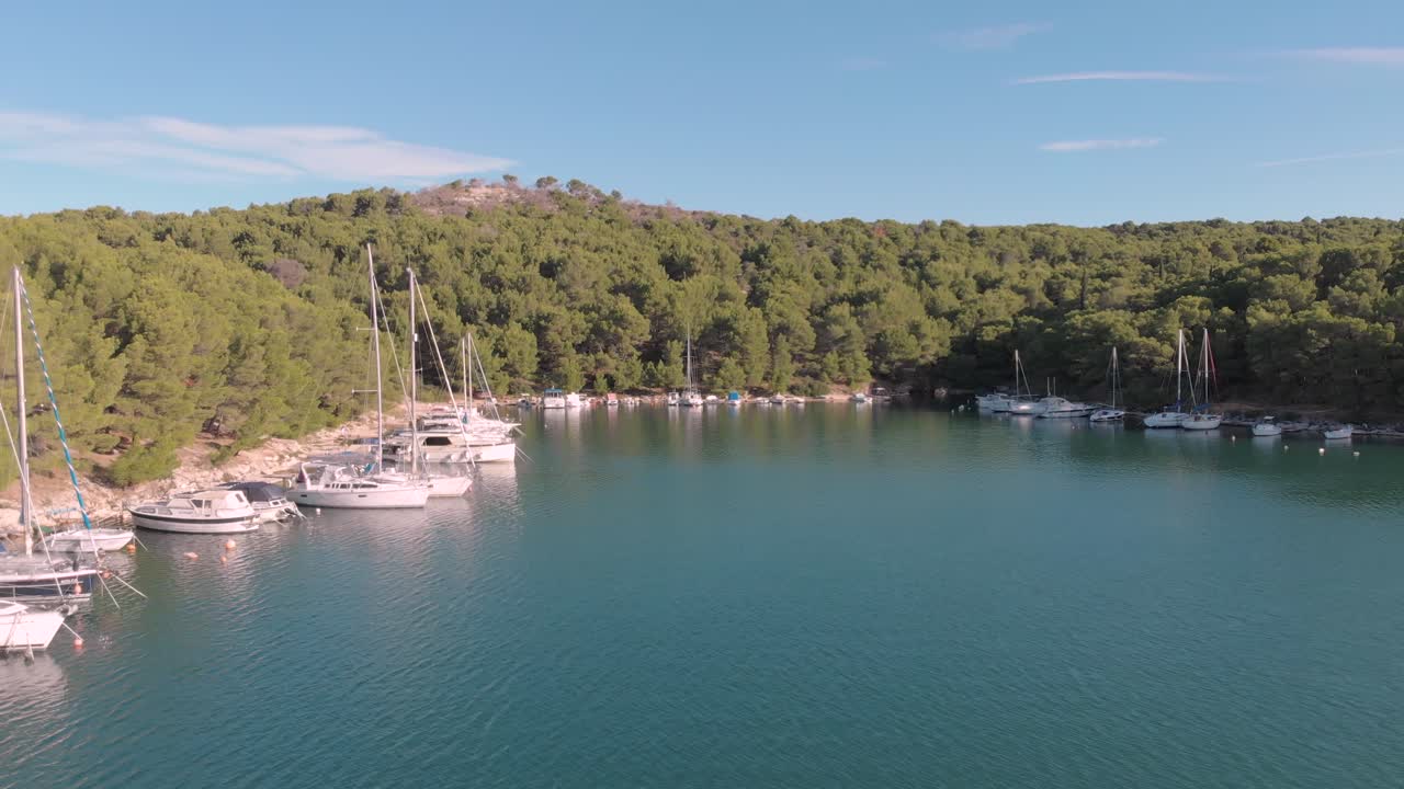 Aerial view of a small private Harbour with luxury yacht and sail boat parking over a clear blue sea during a sunny day of summer