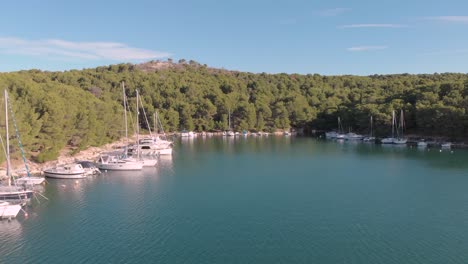 aerial view of a small private harbour with luxury yacht and sail boat parking over a clear blue sea during a sunny day of summer