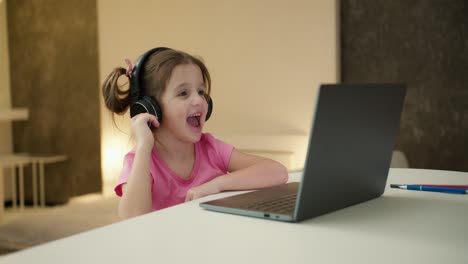 Una-Chica-Guapa-Con-Auriculares-Se-Sienta-En-Casa-Y-Escucha-Música-En-Una-Computadora-Portátil-Jugando-Juegos-De-Computadora