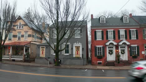 colonial victorian homes decorated for christmas holidays in small town in usa as traffic passes by