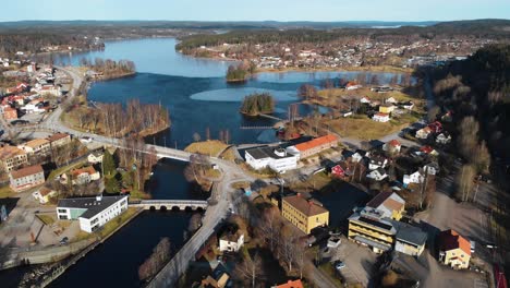 ascend aerial top down showing frozen lake surrounded by small city buildings in bengtsfors, sweden