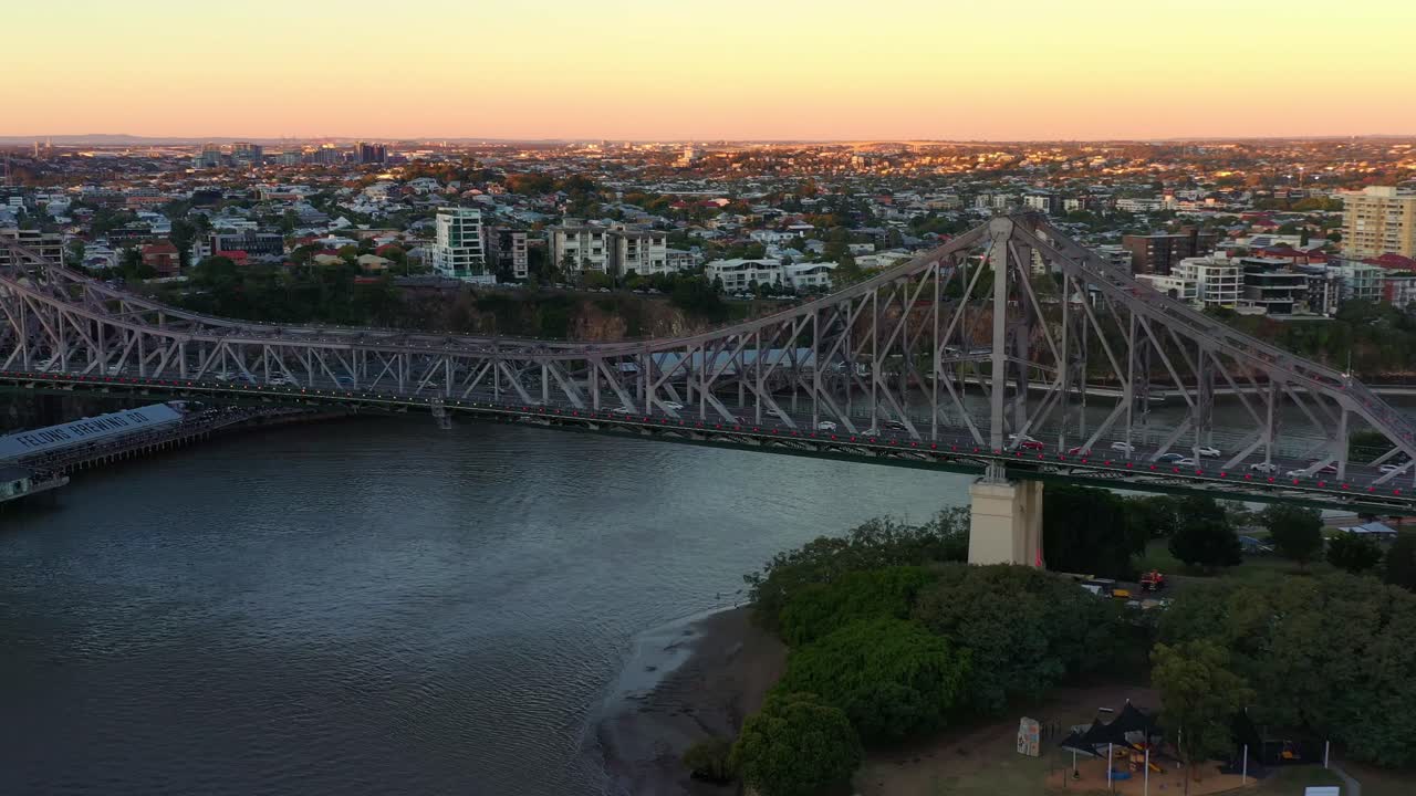 vista aérea del icónico puente de la historia contra el paisaje urbano del nuevo barrio agrícola al atardecer, tráfico de vehículos ocupado cruzando el río brisbane entre kangaroo point y fortitude valley