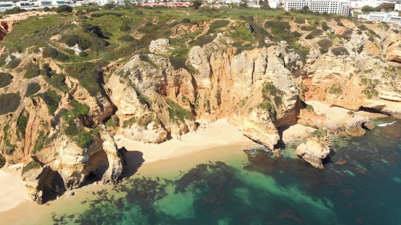 pequeña playa cerrada de camilo en la escarpada costa de lagos, algarve, portugal - amplia toma panorámica aérea