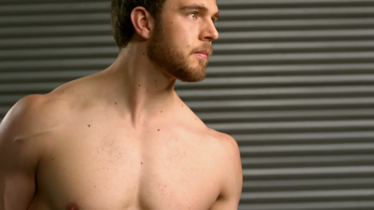 심각한 근육 남자가 덤벨을 들어 올리고 있습니다.