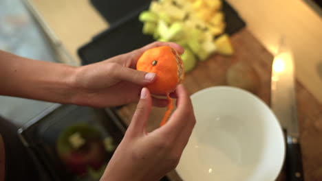 close up of female hands peeling a citrus fruit