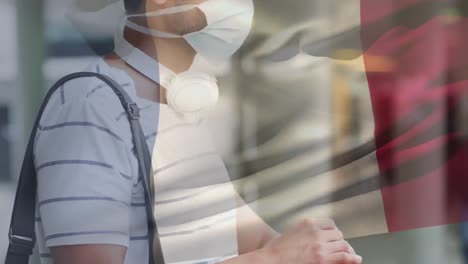 animation of flag of france waving over man wearing face mask during covid 19 pandemic