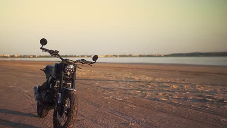 Overview-footage-footage-of-motorcycle-parking-on-the-ground-close-to-the-water-in-sunset,-sunlight-under-water-on-background