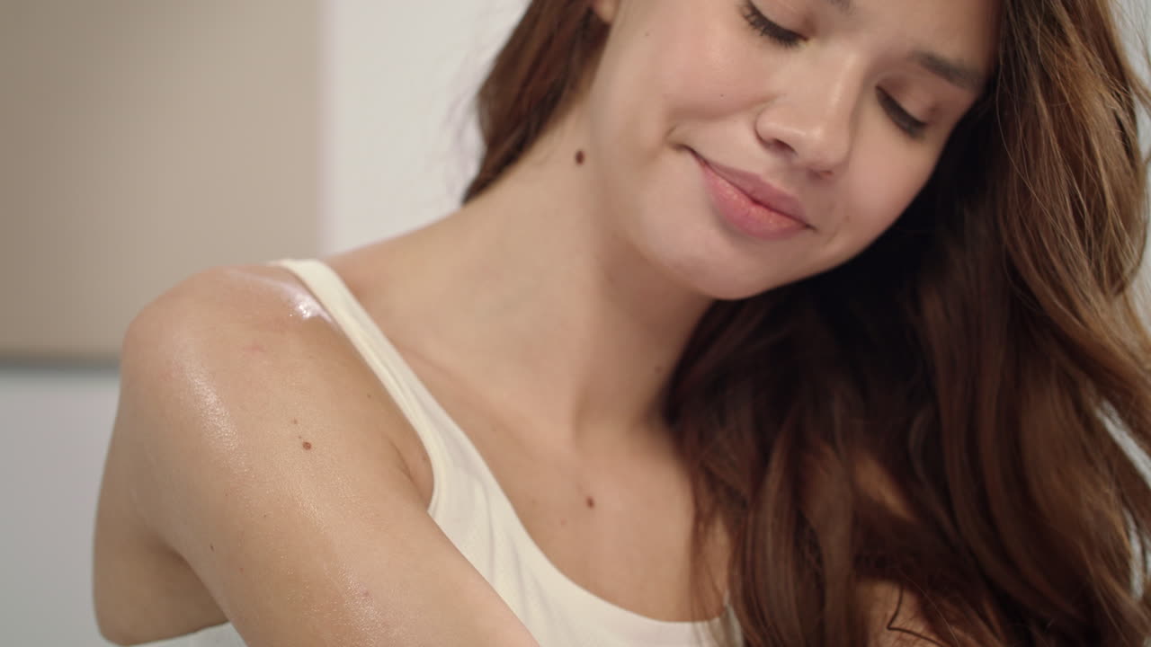 젊은 여성 이 아침 에 바디 로션 을 바르고 있다