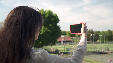 pretty italian woman tourist taking photograph of a park in wimbledon london