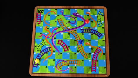 hand rolling dice on snakes and ladders board