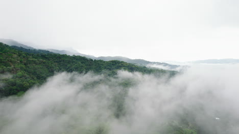 fly above low clouds rolling over tropical landscape