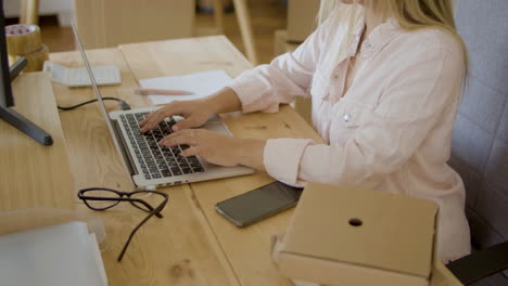 young blonde lady in white shirt working at home