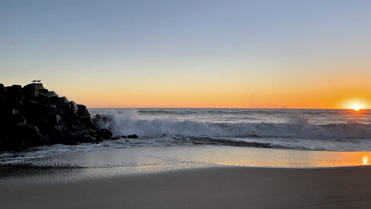 puesta de sol en el embarcadero en el sur de california con olas rompiendo y gaviotas