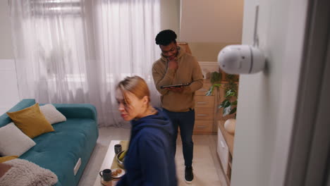 a couple interacting in their modern living room with a visible security camera