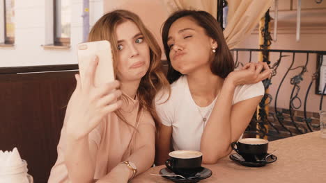 two friends taking a selfie at a cafe