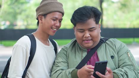 two asian college students looking at a smartphone at break time