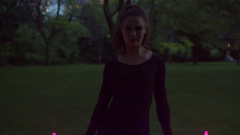 woman spinning and twirling led fans in twilight lit park, medium shot slowmo