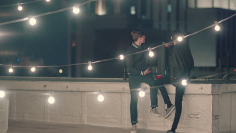 young friends hanging out on rooftop at night chatting having conversation enjoying relaxed urban evening