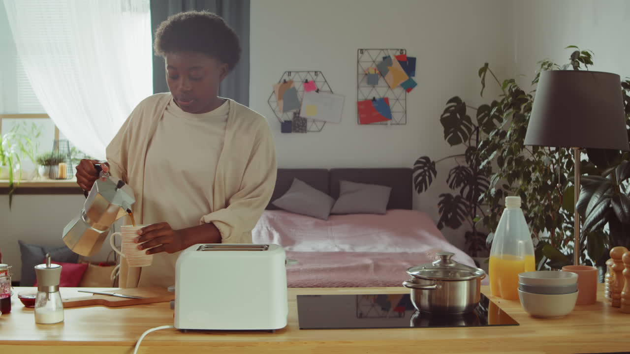 mujer afroamericana bebiendo café en el desayuno en la cocina