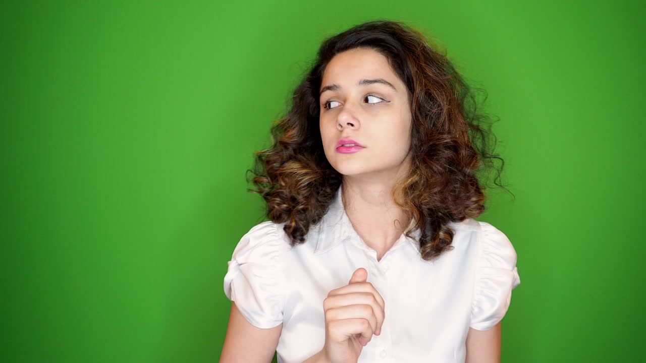 joven bonita en el fondo de la llave de croma verde muy asustada y asustada, desesperada por algo, cubriendo la boca con las manos. espacio de copia. 4k